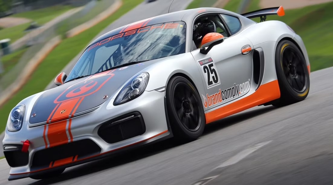 Silver Porsche race car on track with gray and orange graphic accents