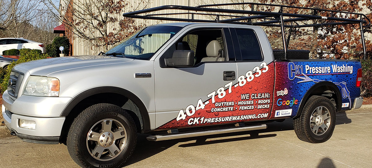 Silver CK1 Pressure Washing pickup with red and blue graphics across the doors and bed.