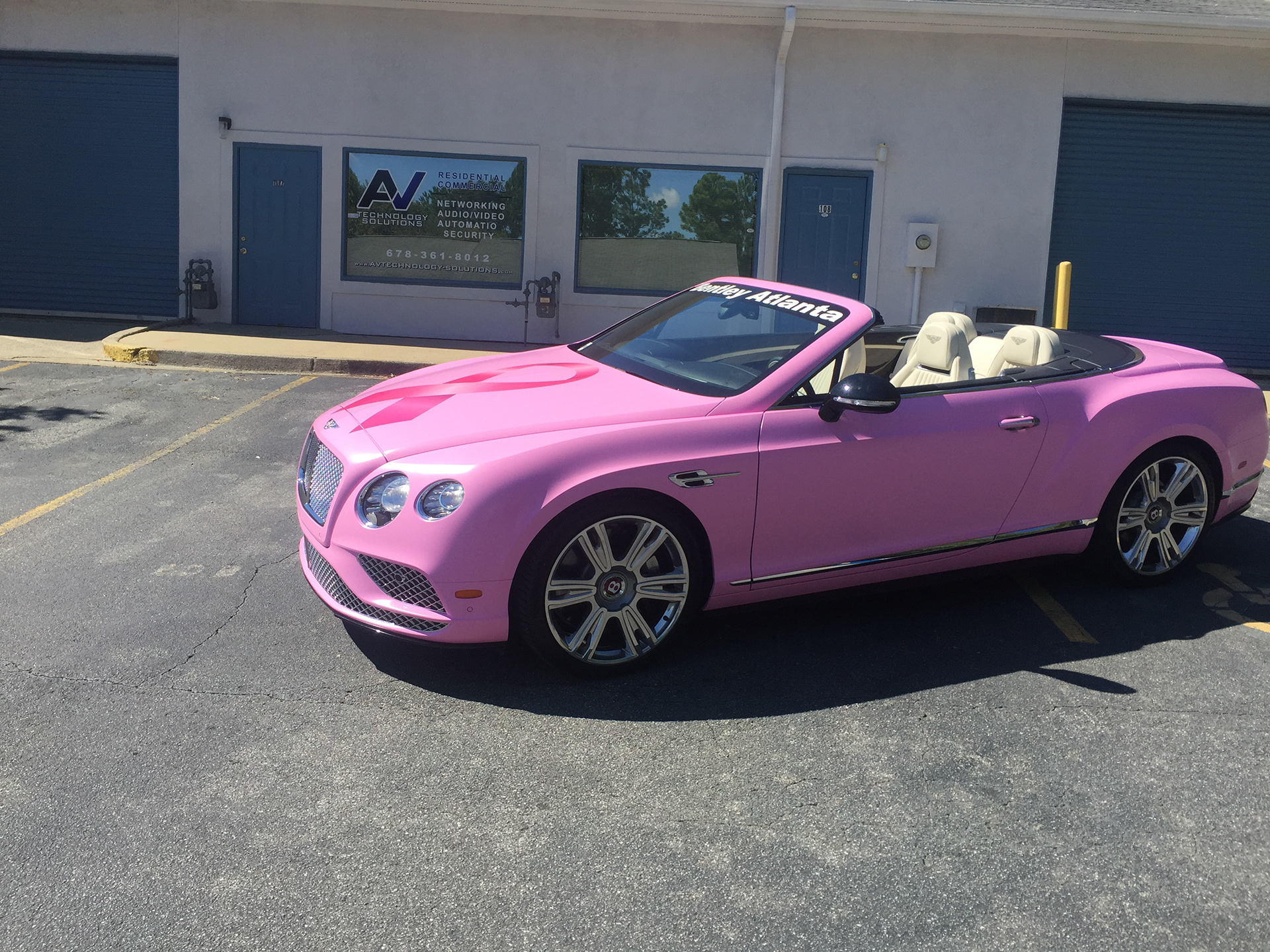 Pink Bentley convertible with a ribbon graphic on the hood and cream-colored seats.