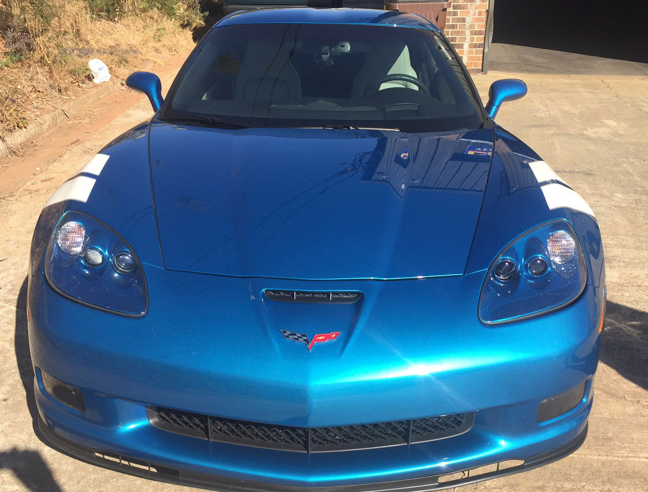 Front view of a blue Chevrolet Corvette with paired white accent stripes over the front fenders.