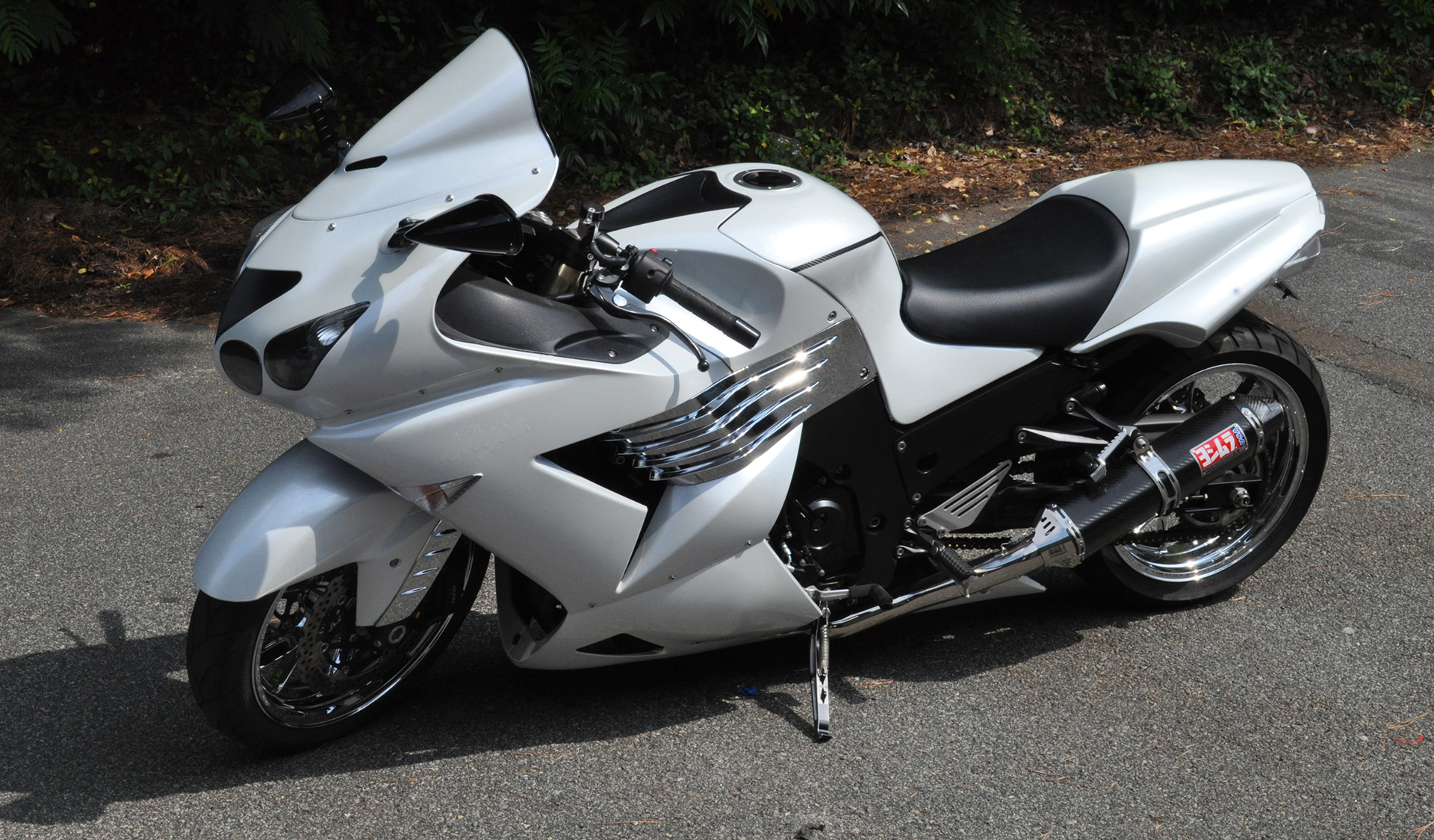 White and silver Kawasaki Ninja sport motorcycle with black and chrome details parked outdoors.