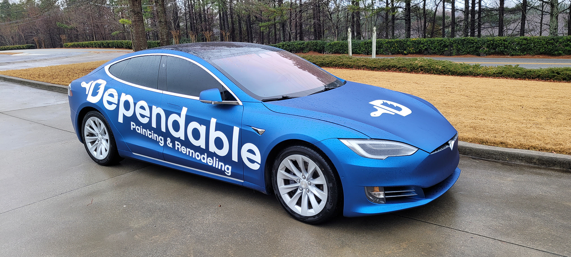 Blue Dependable Painting and Remodeling sedan with white lettering across its doors and a white hood emblem.