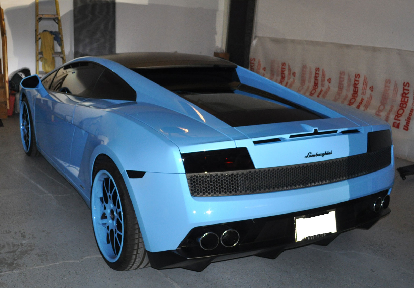 Light blue Lamborghini with a black roof and blue wheel accents, viewed from the rear quarter.