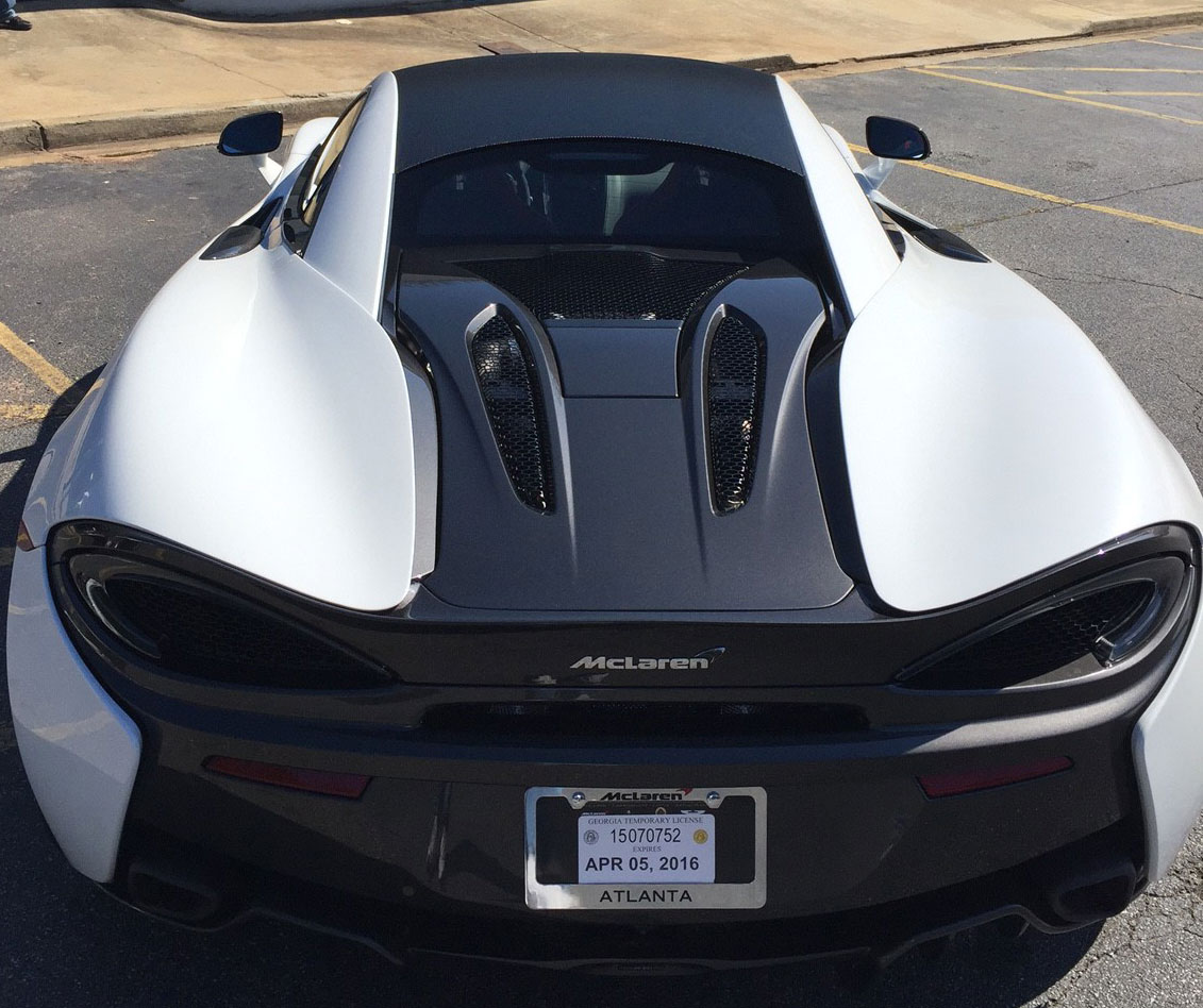 Rear view of a McLaren with contrasting white body panels, black roof, and dark engine cover.
