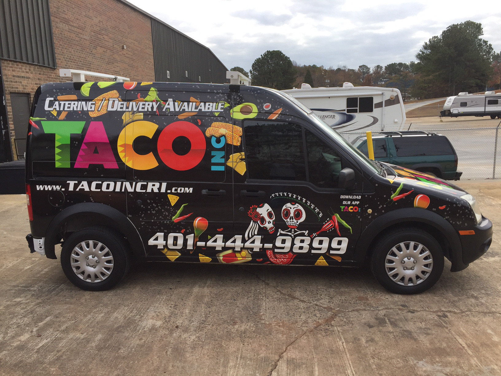 Taco Inc catering van with a black wrap, multicolored lettering, food illustrations and skeleton musicians.