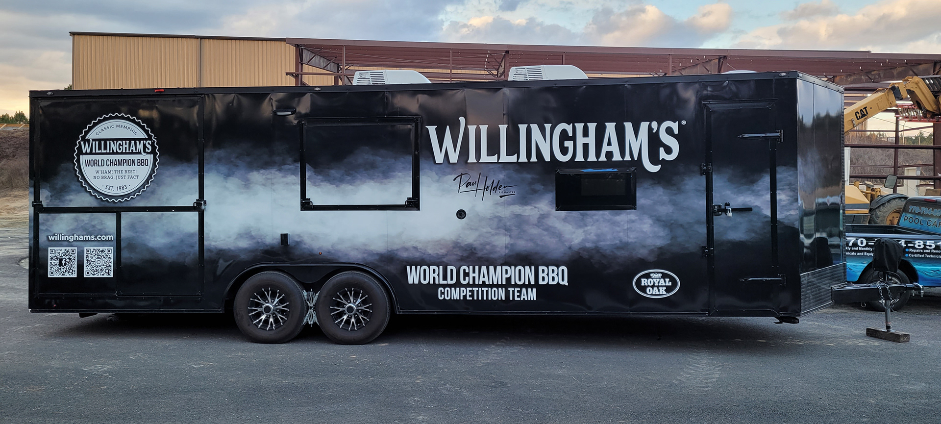 Willingham's tandem-axle BBQ trailer with a black and gray smoky wrap and large white branding.